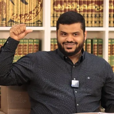 أحمد السيد في مجلس أمام رفوف الكتب
