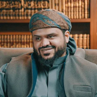 أحمد السيد بعمامة مطرّزة أمام رفوف الكتب