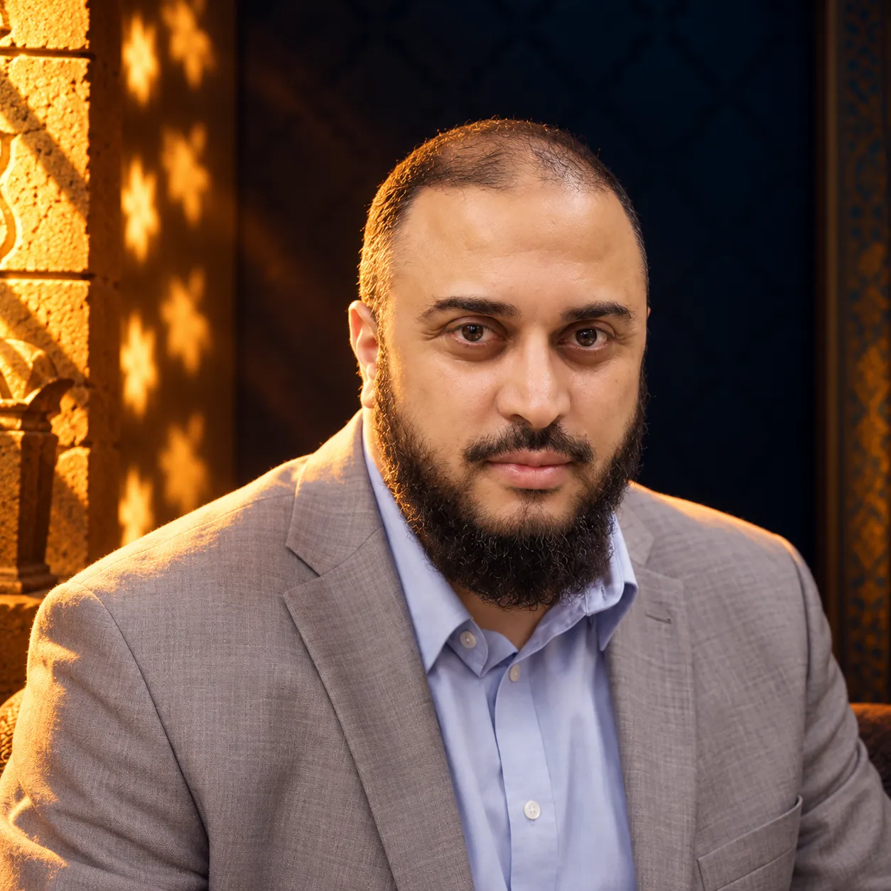 صورة سامي عامري بسترةٍ رمادية وقميصٍ أزرق